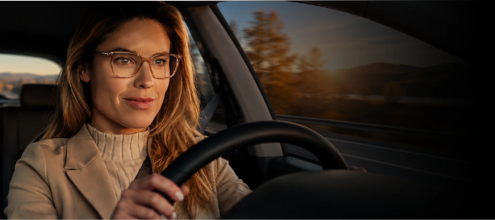Mujer conduciendo con lentes Varilux al atardecer